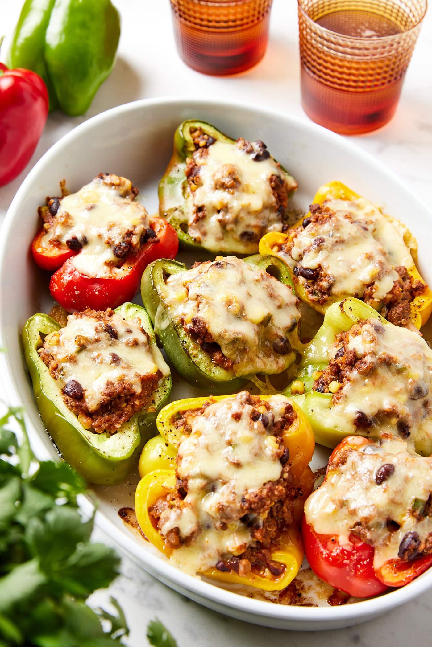 A baking dish holding stuffed peppers with melted cheese.