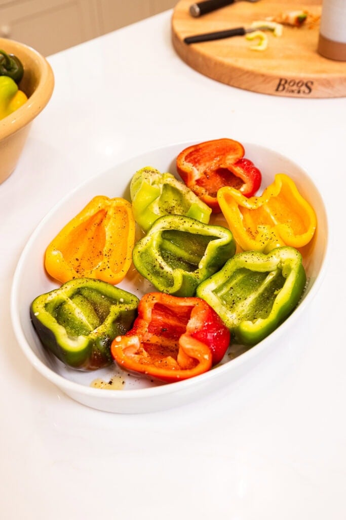 Halved bell peppers sit in a baking dish.