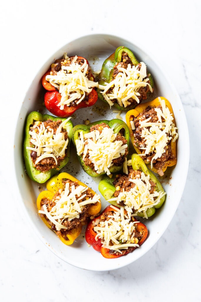 Stuffed bell peppers sit in a baking dish before being baked.