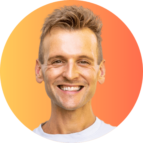 Kaleb Wyse wearing gray shirt standing in front of an orange to yellow background smiling.