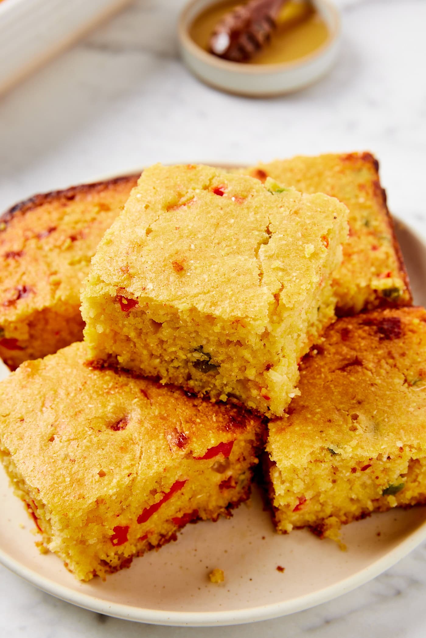 Slices of brown butter jalapeño cornbread stacked on a plate with specks of green and red.