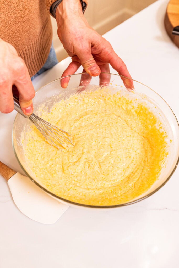 Whisking together ingredients to create a cornbread batter.