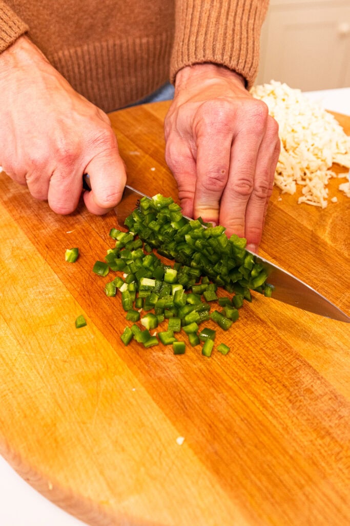 Dicing jalapenos on a wooden cutting board.