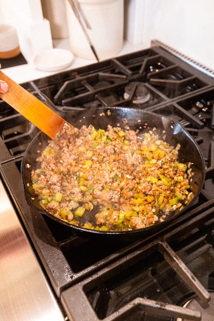Sausage, onion, celery, and herbs all cook in a skillet before getting added to stuffing.