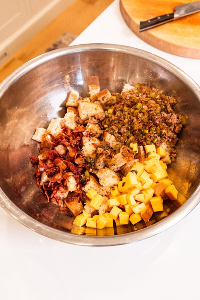 Ingredients for bacon and cheese stuffing being placed in a bowl before getting mixed together.
