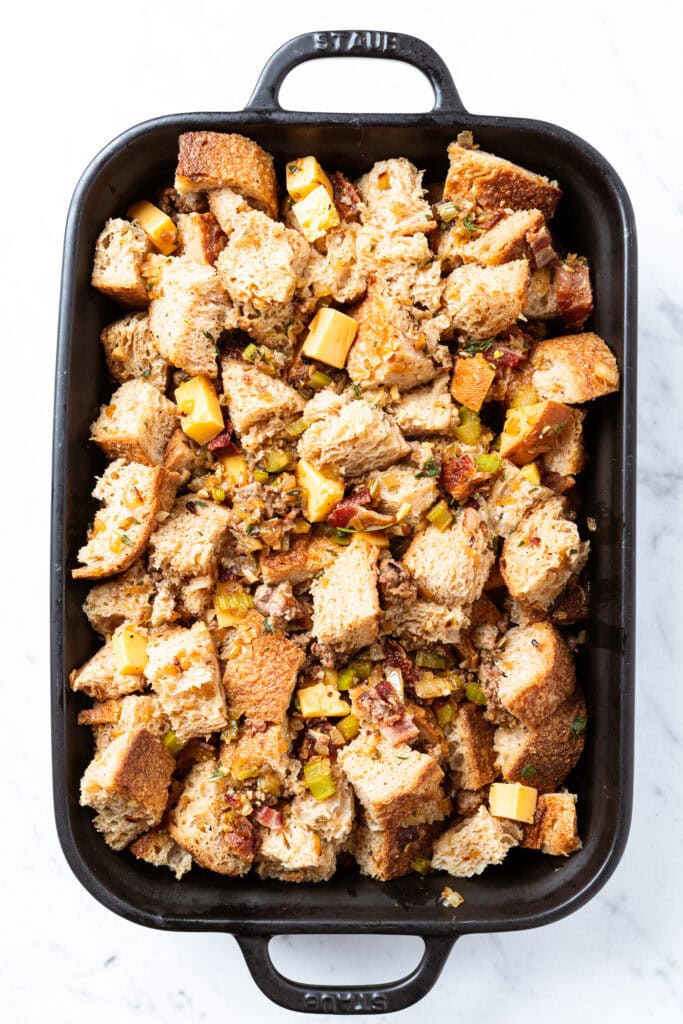 Stuffing sitting in a black baking dish before going into the oven to bake.