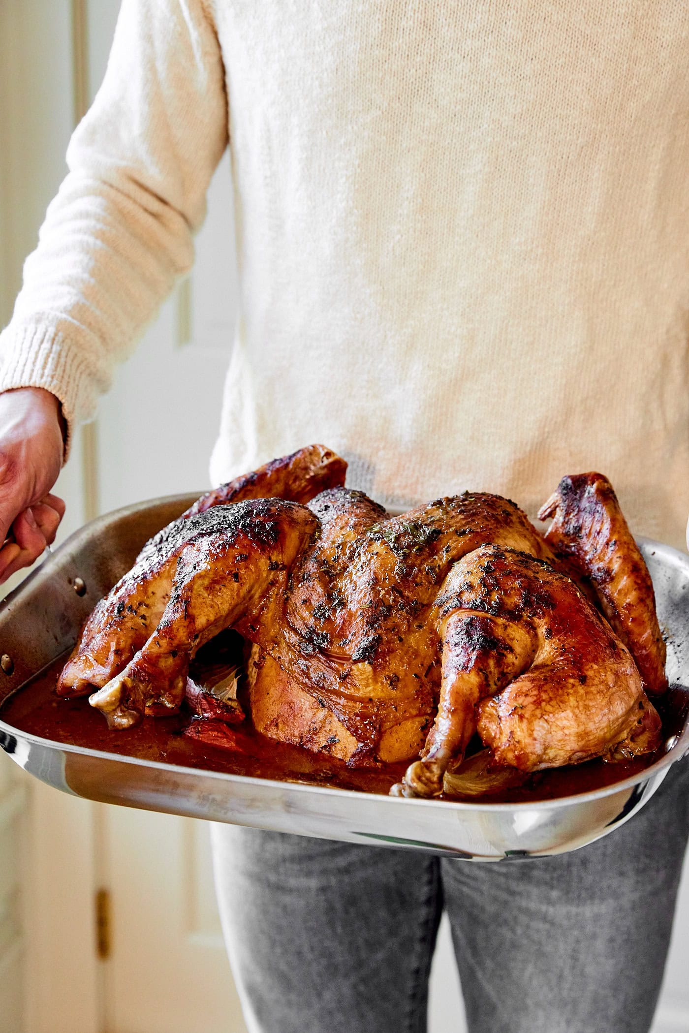Kaleb holding large roasting pan filled with roasted spatchcocked turkey with basting liquid in pan.