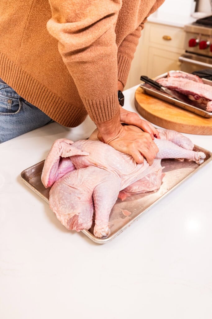 Pressing down on a full Thanksgiving turkey to break the wishbone prior to cooking.