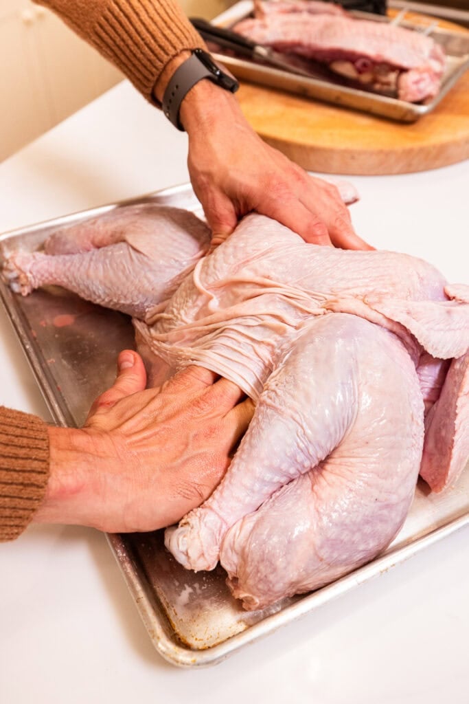 Rubbing a dry brine underneath the skin of a turkey prior to cooking.