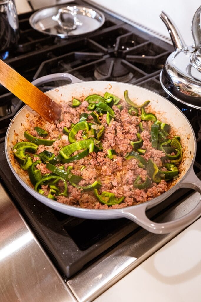 Peppers and sausage cook in a skillet.