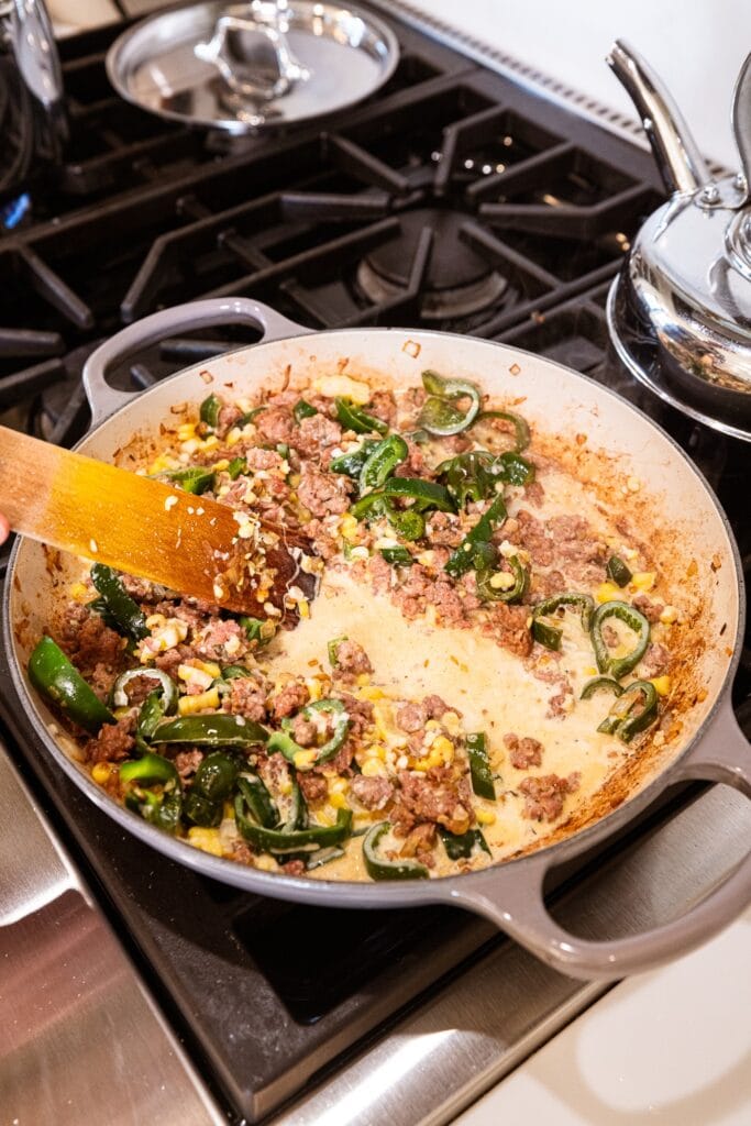 Cream gets added to sausage with peppers and sweet corn to form a sauce.