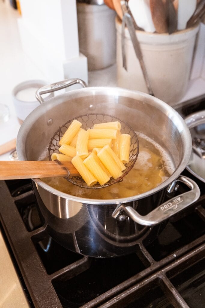 Pasta gets pulled out of a pot on the stove.