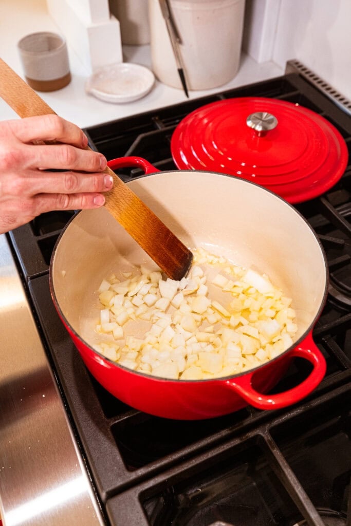 Onion sautes in a pot on a stove.