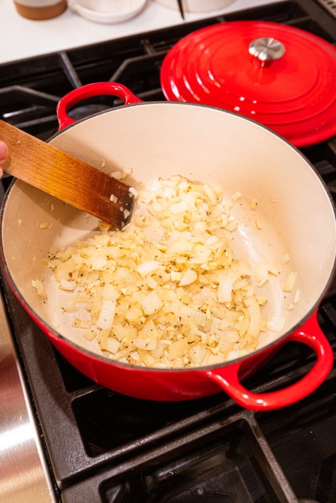Onion turns translucent after sauteing in a pot on a stove.