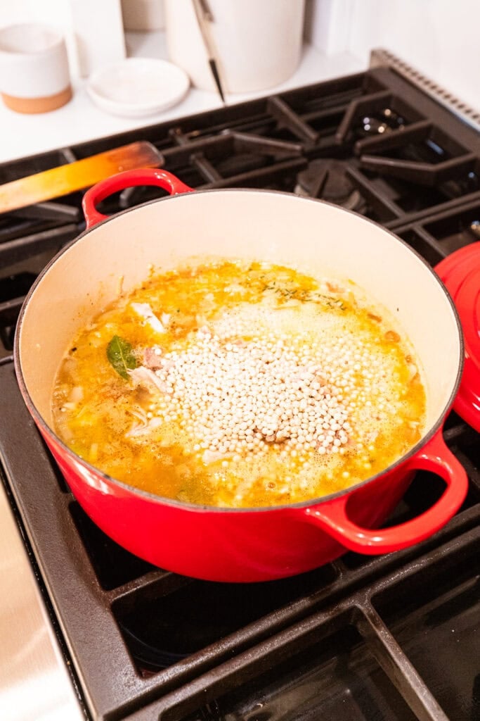Couscous gets added to a pot with turkey stock to cook.