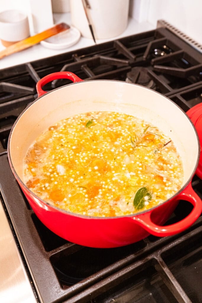 Soup with couscous simmers over heat.