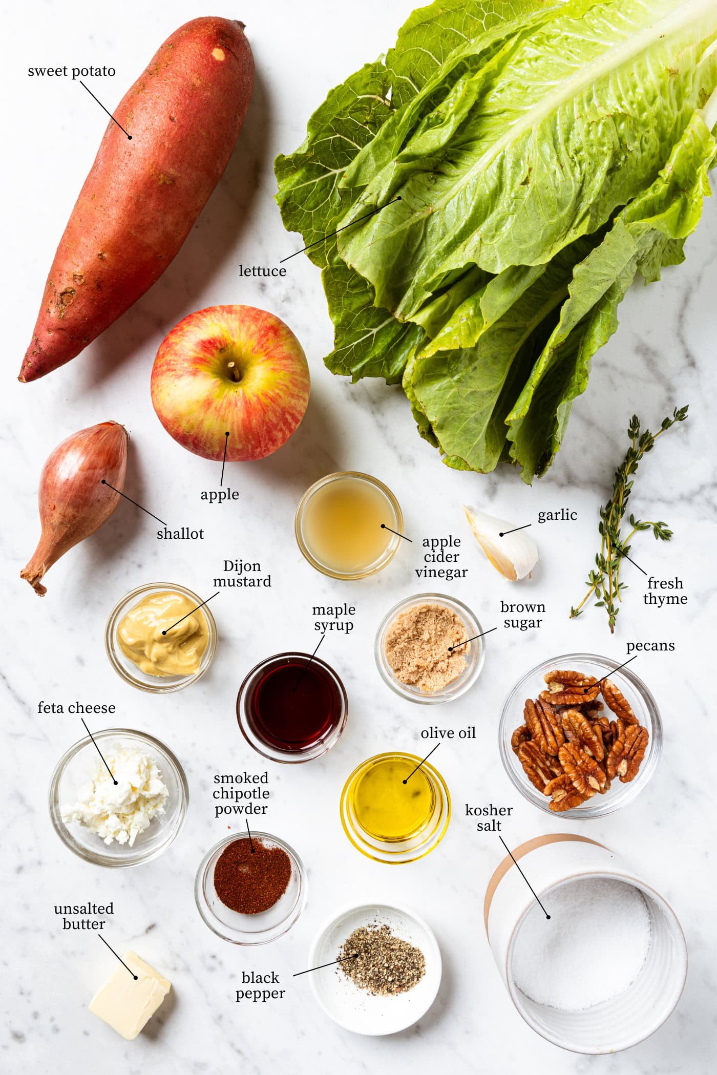 White marble surface filled with ingredients needed for fall sweet potato salad including lettuce, apple, and more.