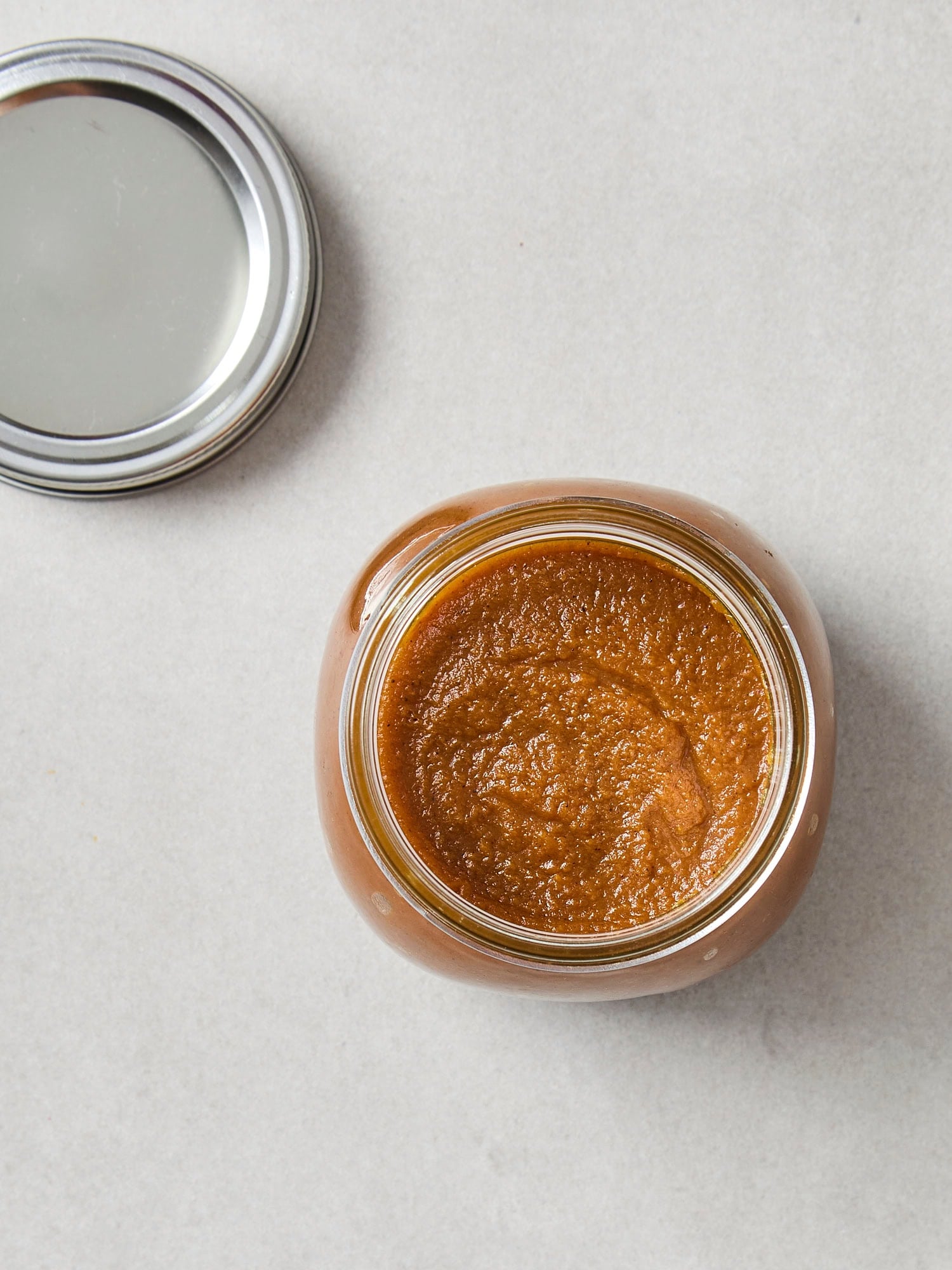 Pumpkin butter in a glass jar after being cooked on the stove.