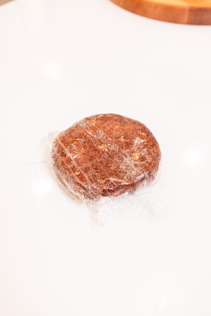 A disk of chocolate pie dough crust in a plastic wrap.