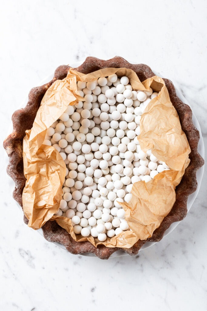 Adding pie weights to a pie crust prior to par-baking.