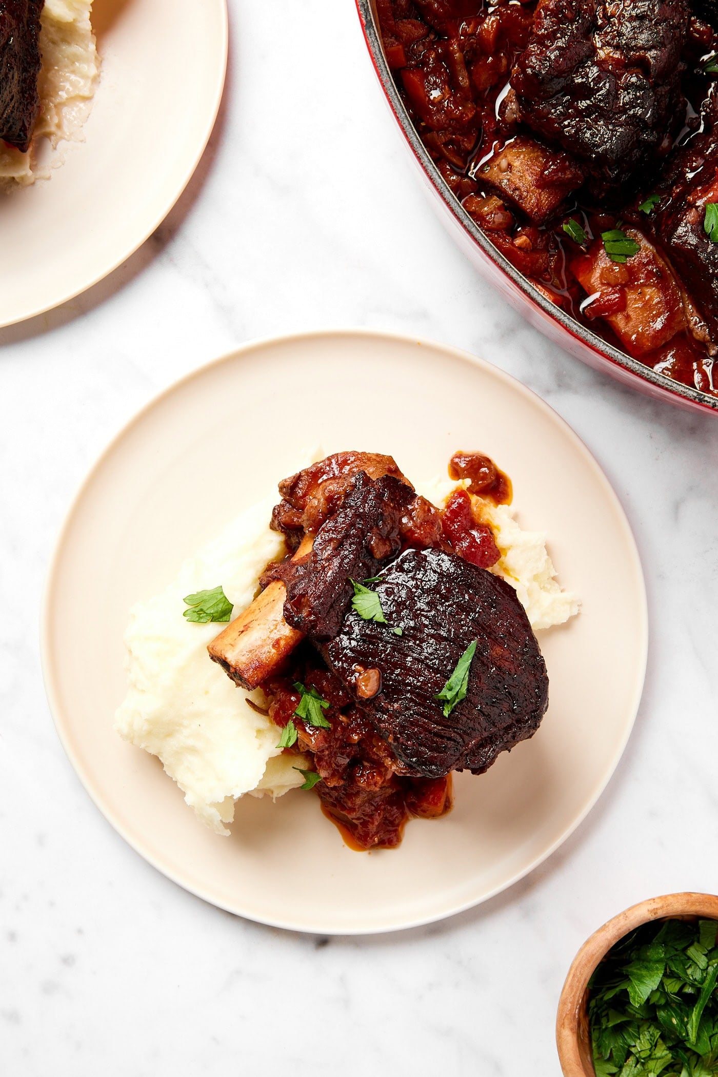 Short ribs served with mashed potatoes sit on a plate.