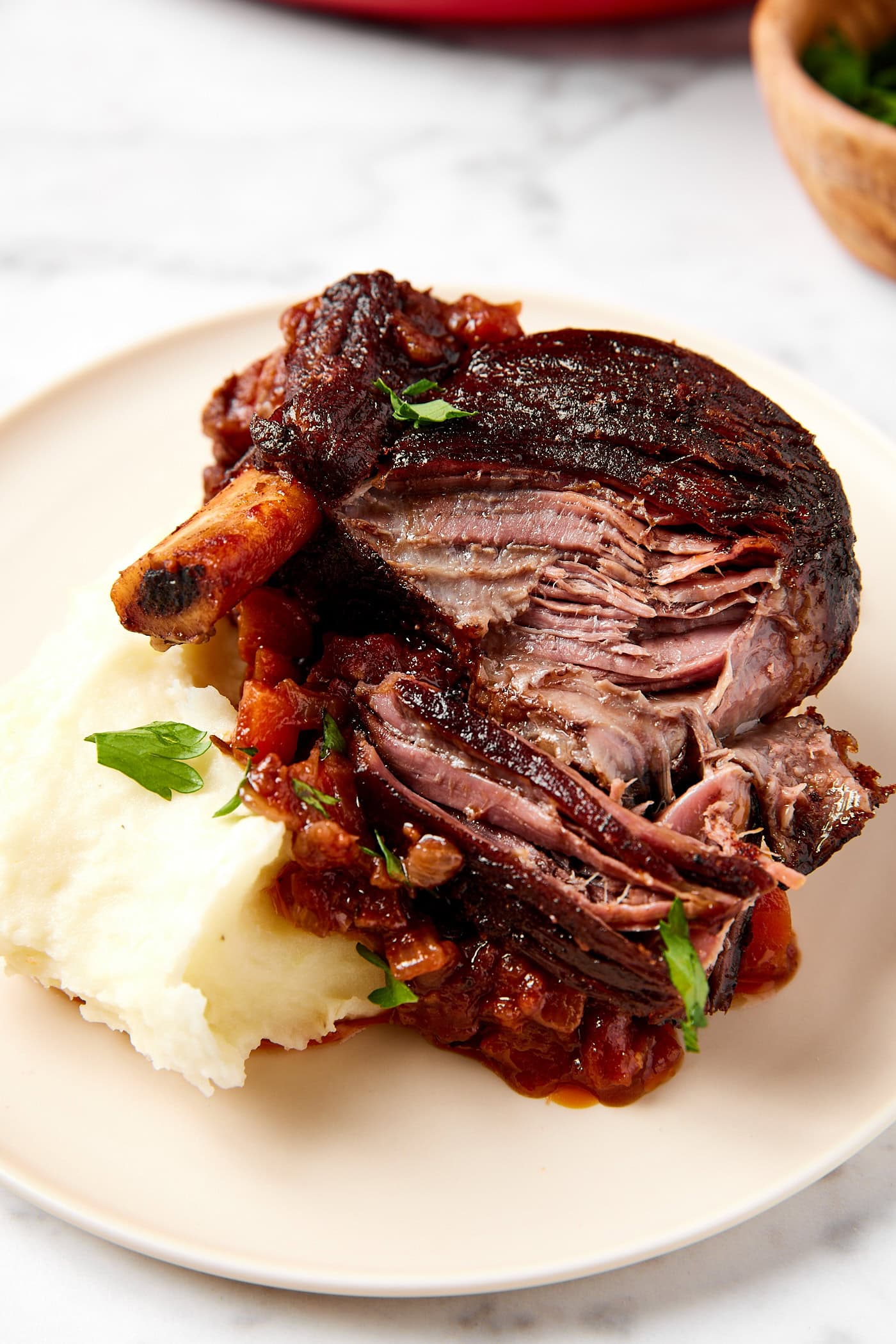 Braised short ribs served with mashed potatoes sit on a plate.