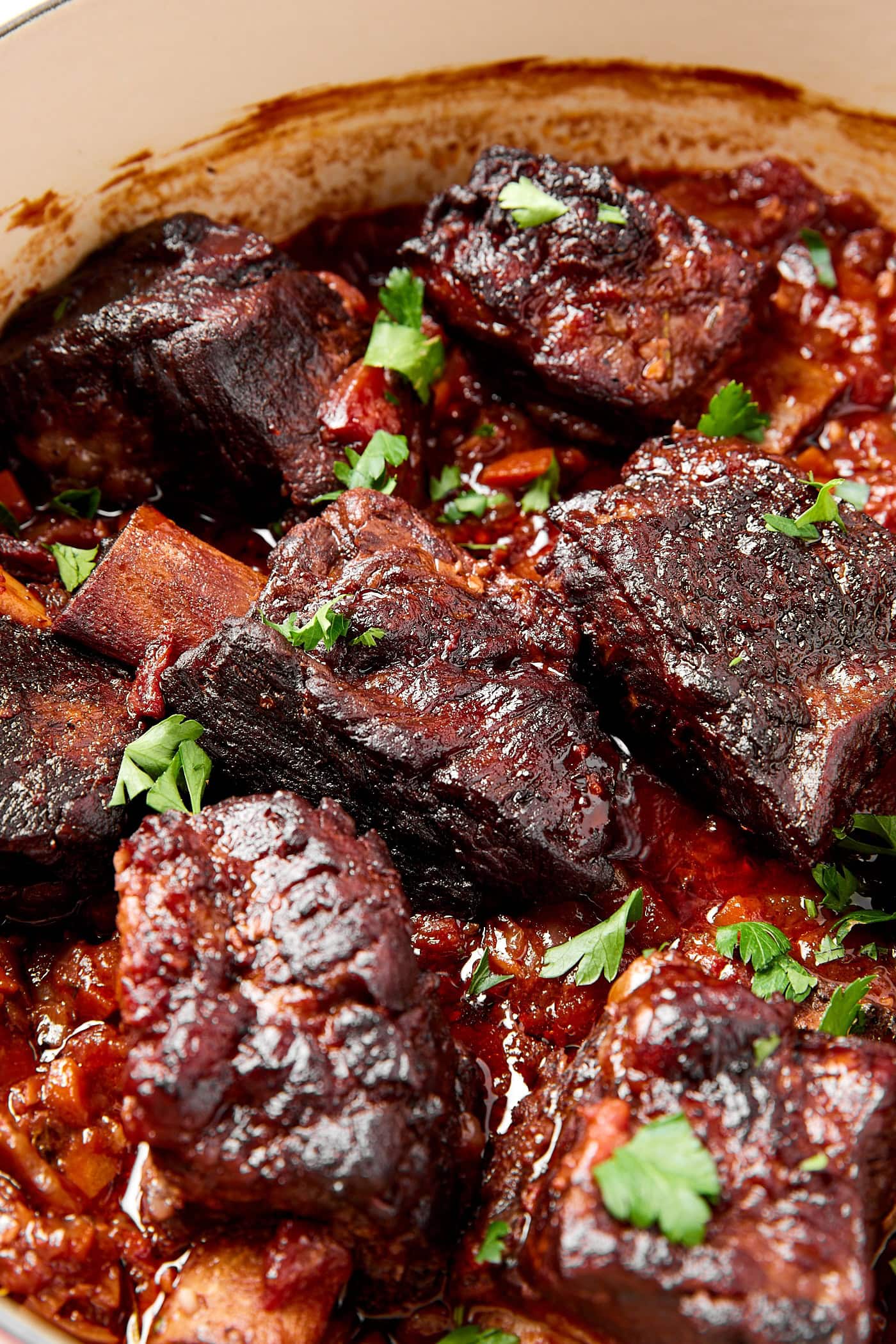 Short ribs sit in a sauce after cooking in a Dutch oven.