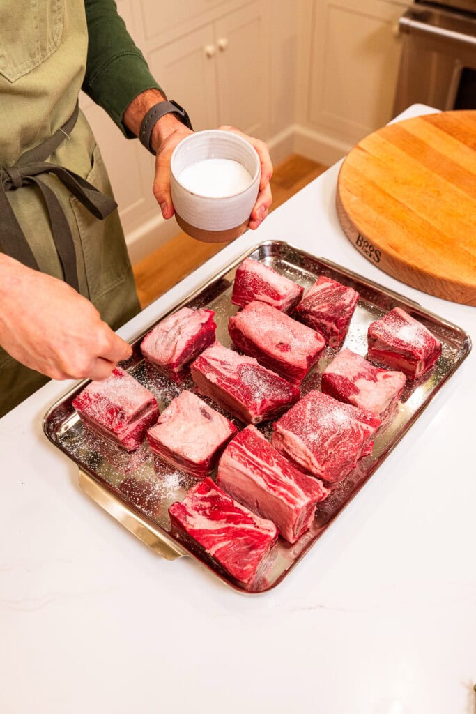 Seasoning all sides of short ribs before cooking them.
