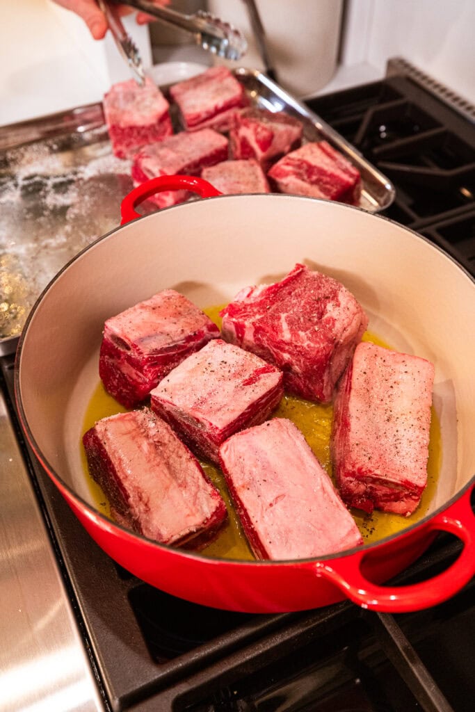 Short ribs cook in a Dutch oven on a stove.