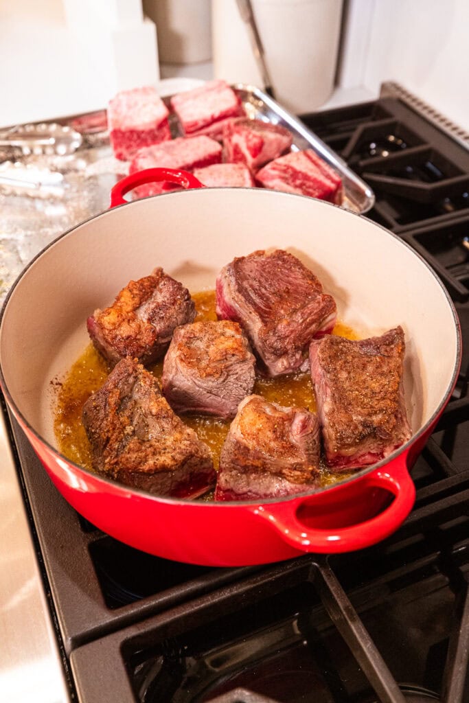 Short ribs cook in a Dutch oven over heat.