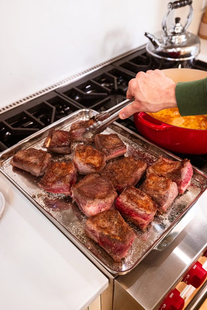 Placing partially cooked short ribs on a tray.