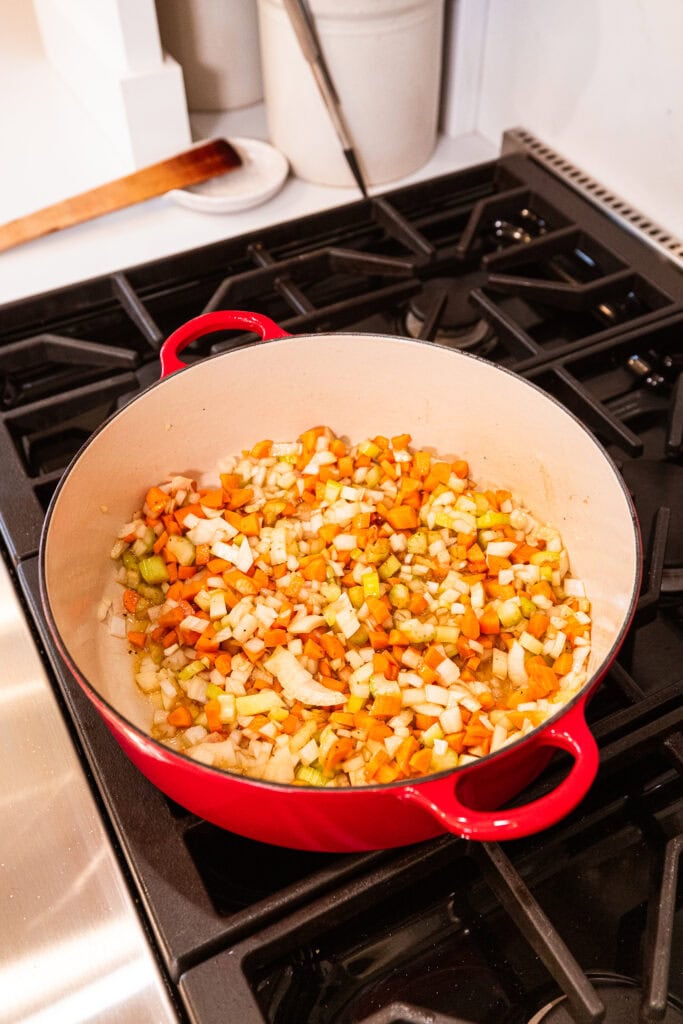 Aromatics cook in a Dutch oven over heat.