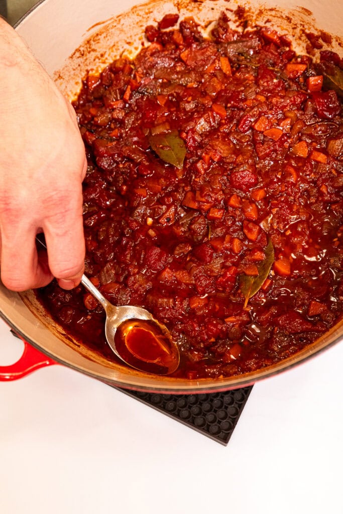 Spooning off the fat from a sauce for a meat sauce.
