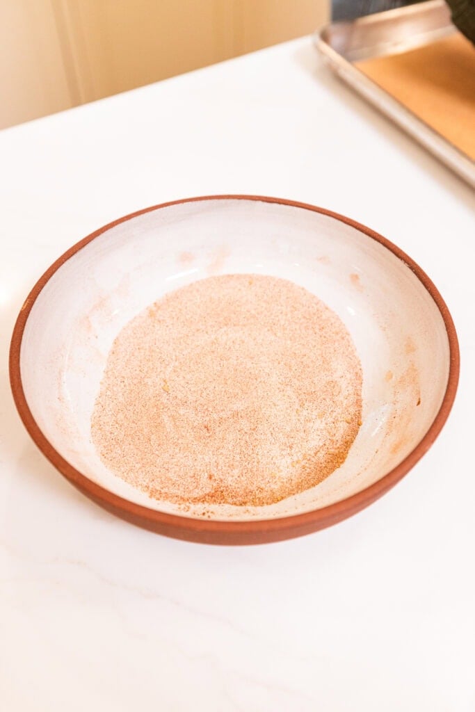 A spice mix of cinnamon, ground ginger, cloves, and sugar sit in a bowl.