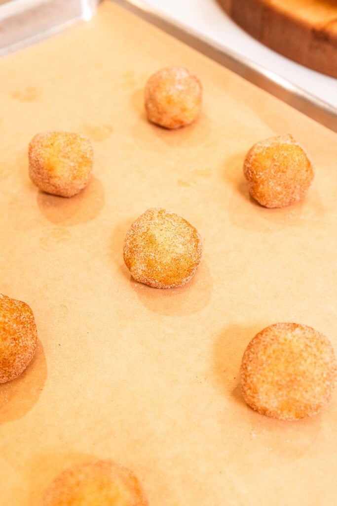 Placing balls of snickerdoodle cookie dough on a baking sheet to bake.