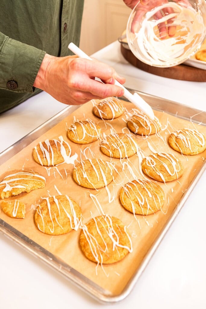 Drizzling white chocolate over cooled snickerdoodle cookies.