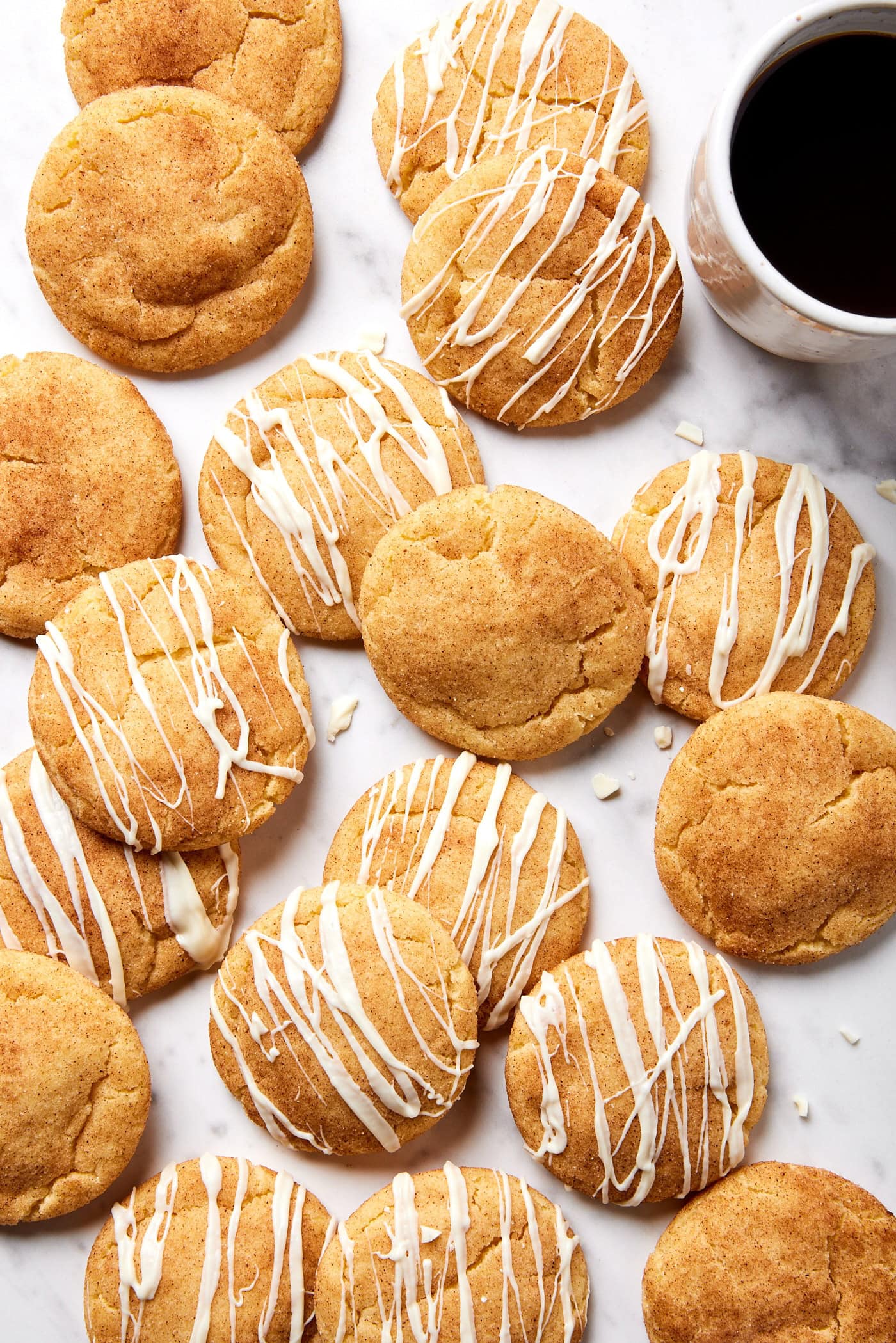 Pile of brown butter Snickerdoodle cookies with icing on top of some all on marble surface.