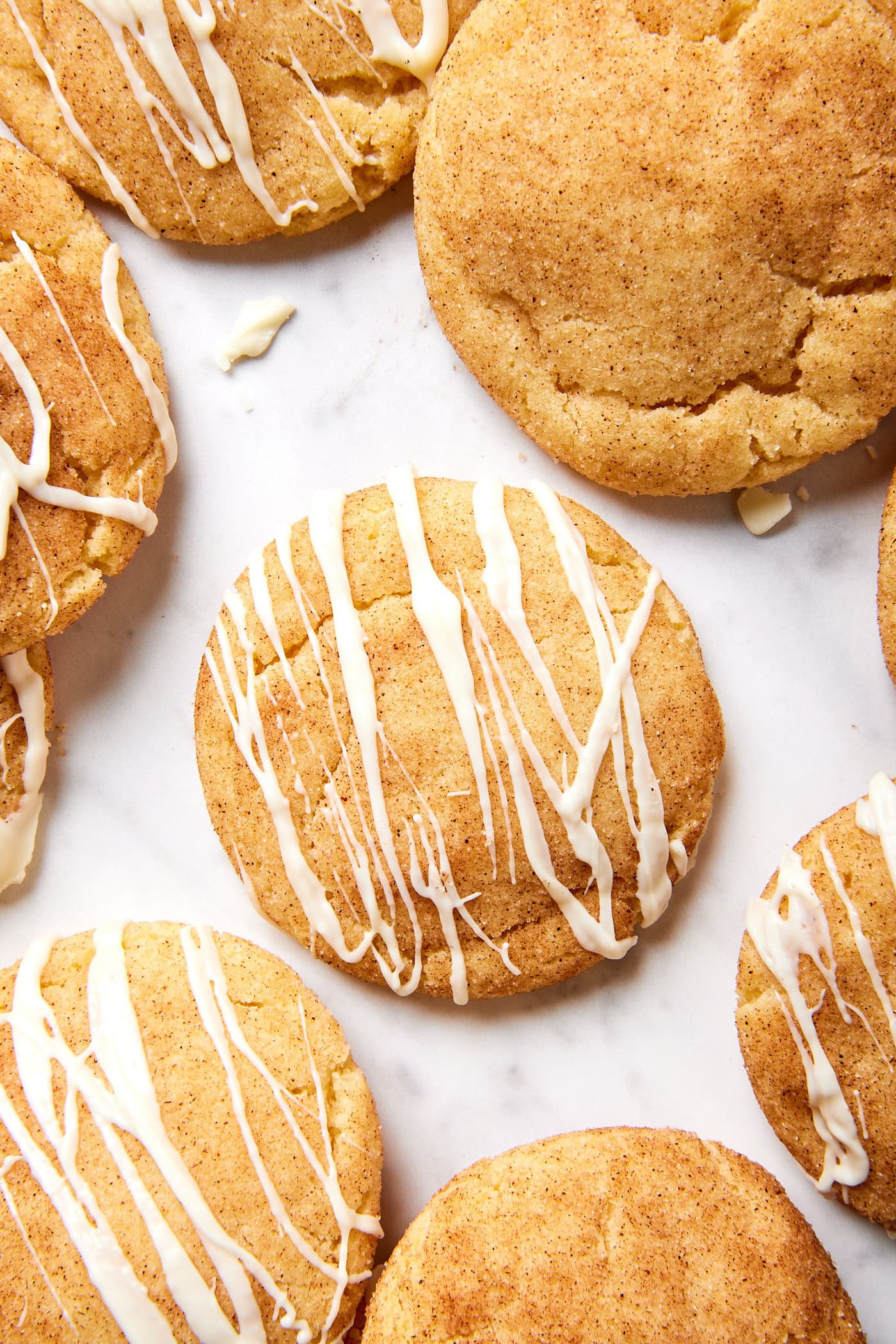 Snickerdoodle cookie with white chocolate drizzle on top all on marble surface.