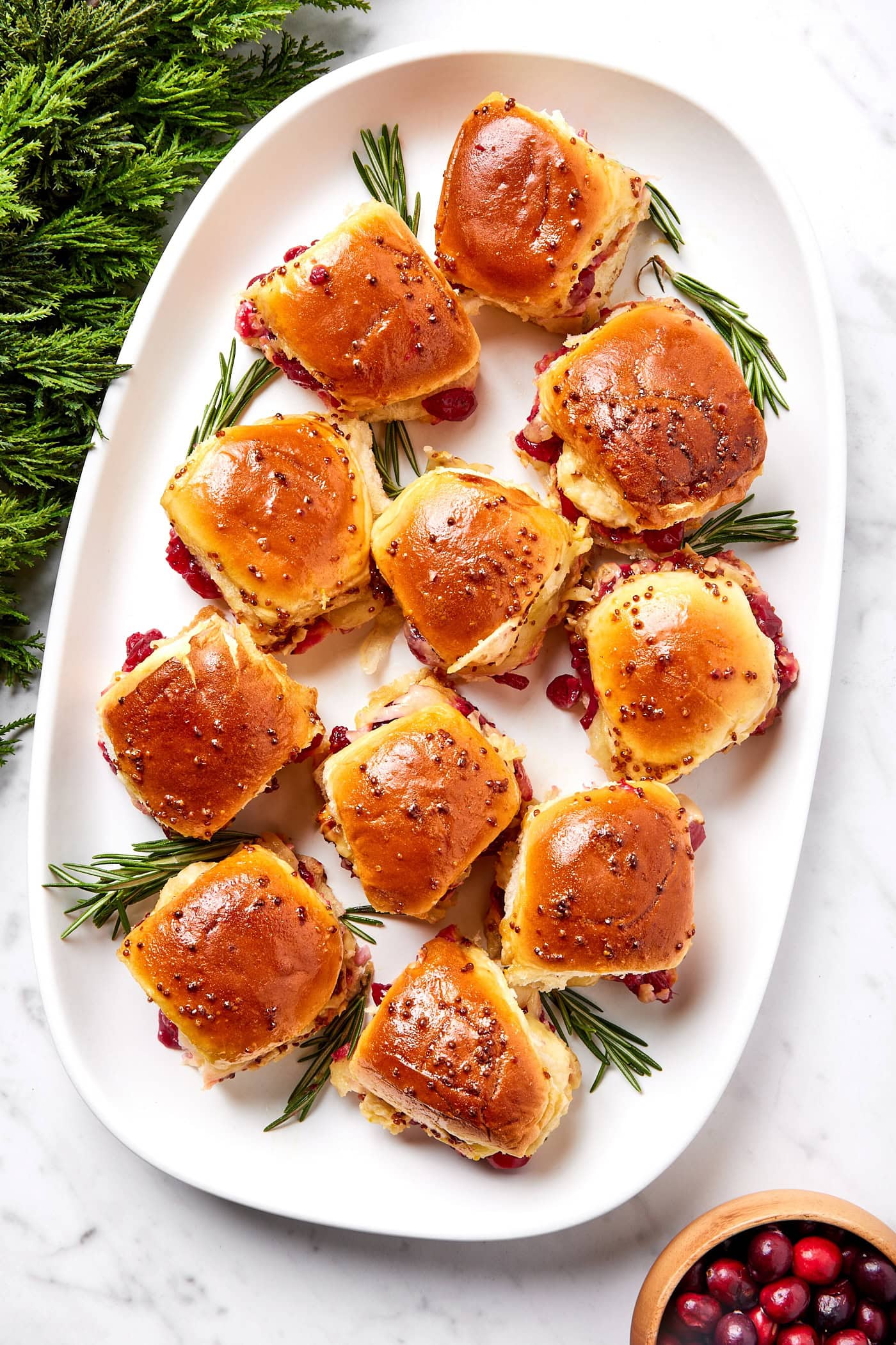 Small meatball sandwiches sit in a large serving platter.