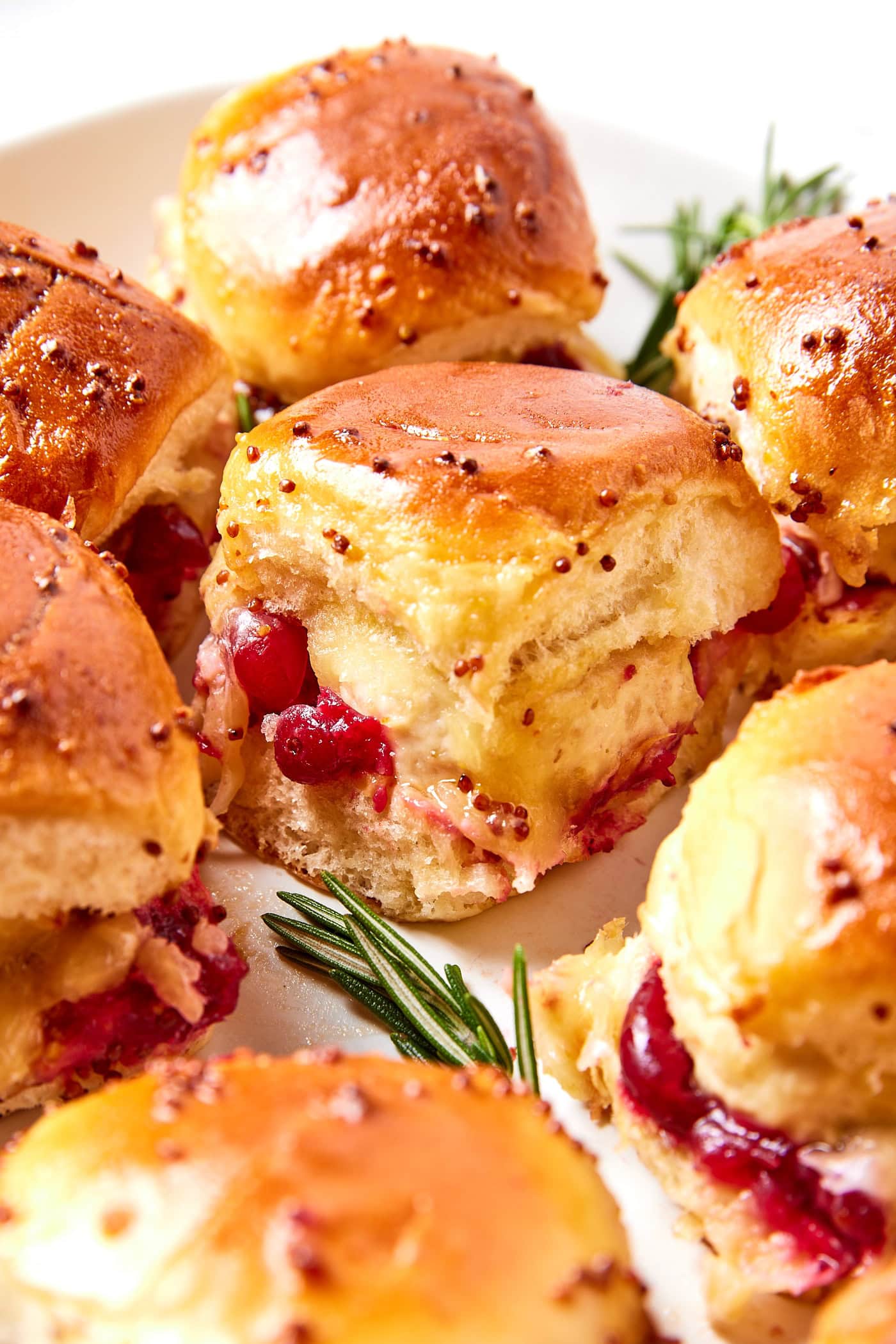 Chicken meatball sliders with cranberry sauce and Dijon mustard on a platter.