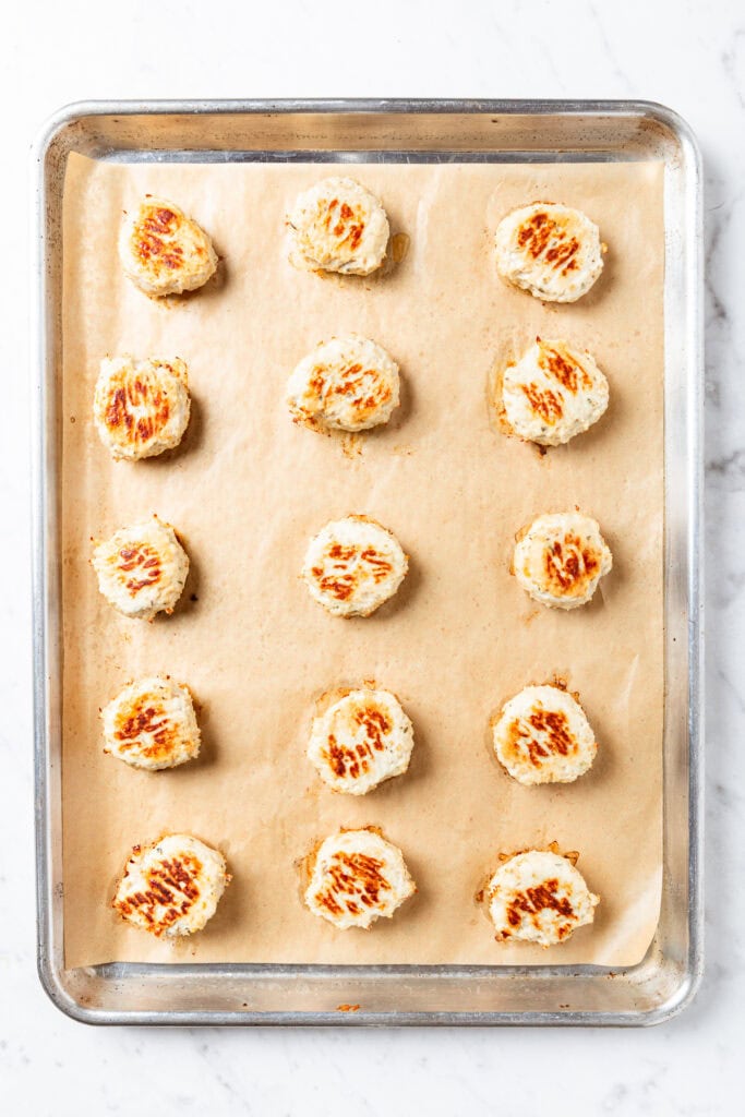 Baked chicken meatballs on a baking sheet.