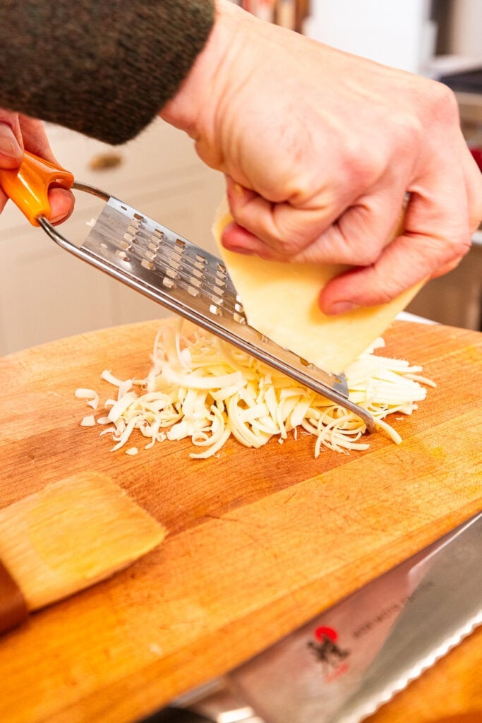 Shredding a block of cheddar cheese.