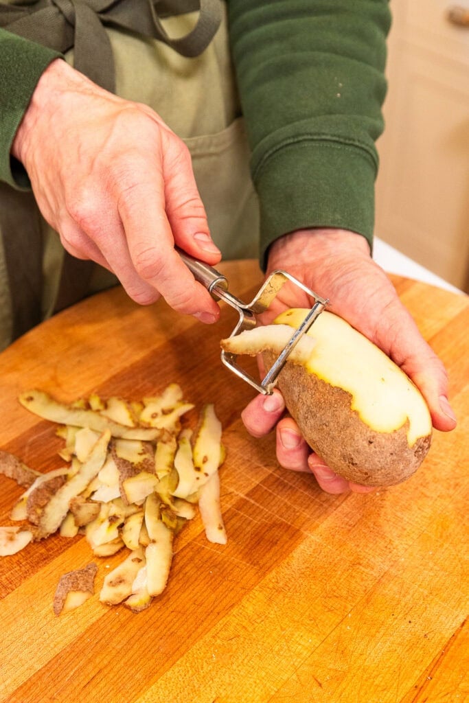 Hand peeling a potato.
