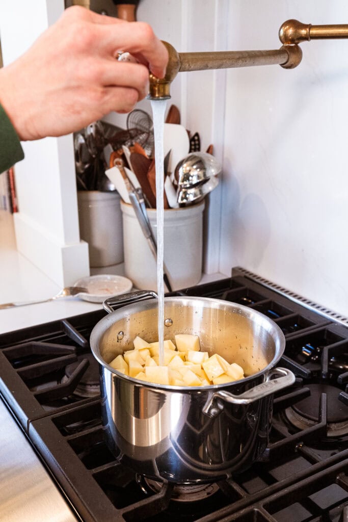 Adding water to a pot to cook the potatoes.