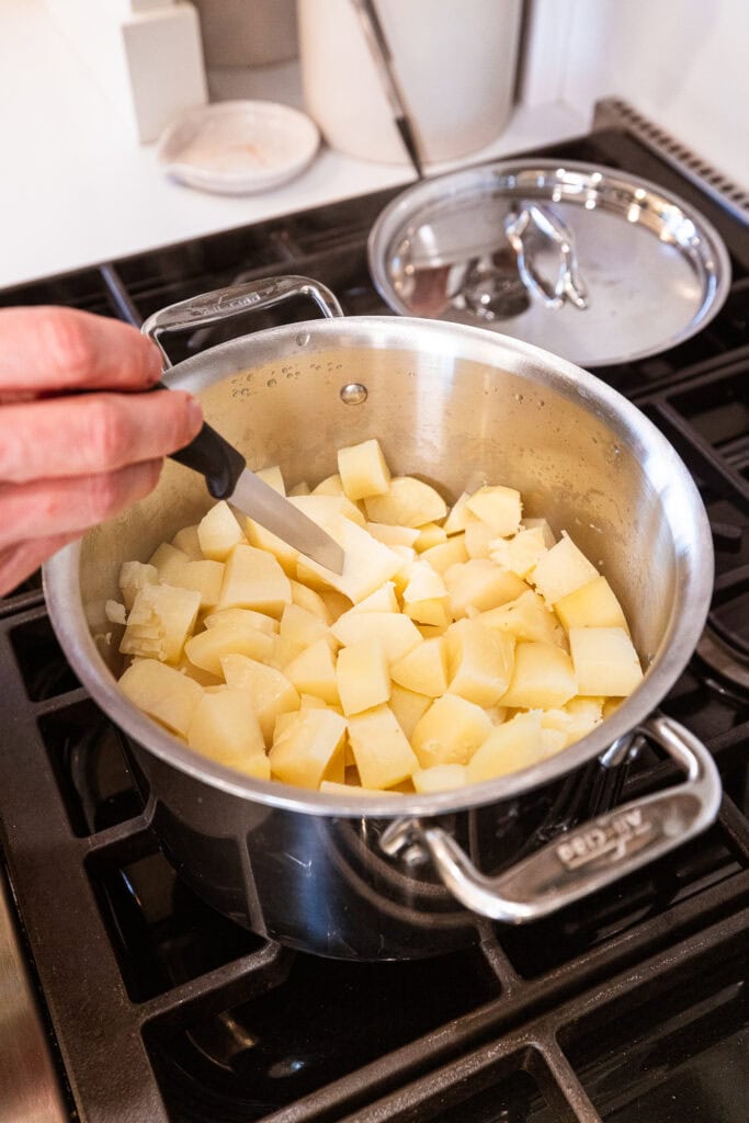 Checking the tenderness of cooked potatoes with a knife.