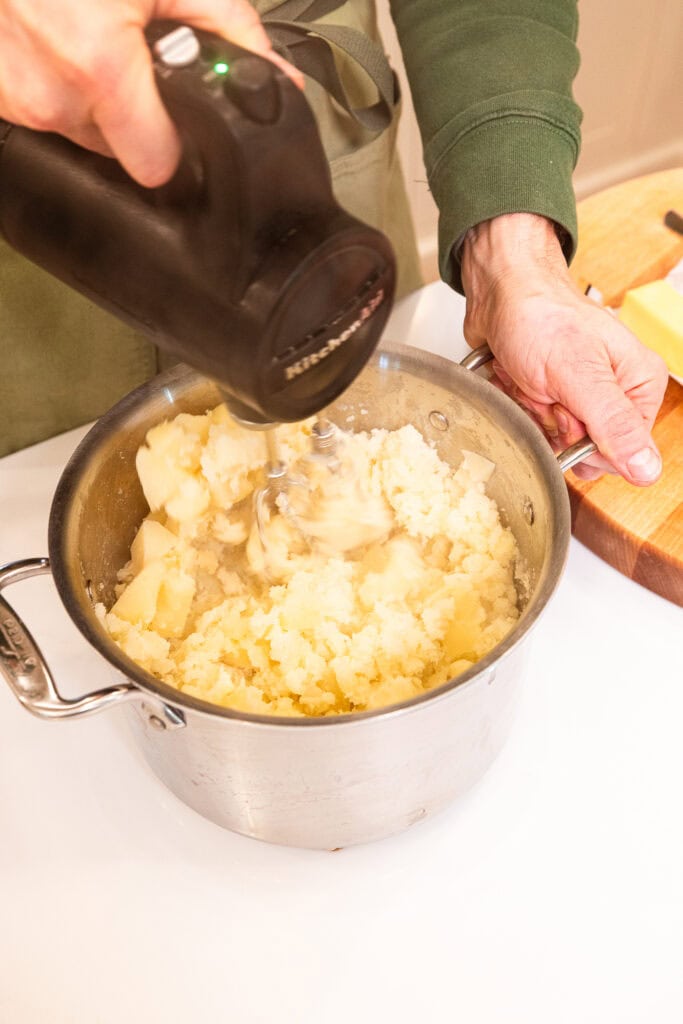 Mixing cooked potatoes with an electric mixer.