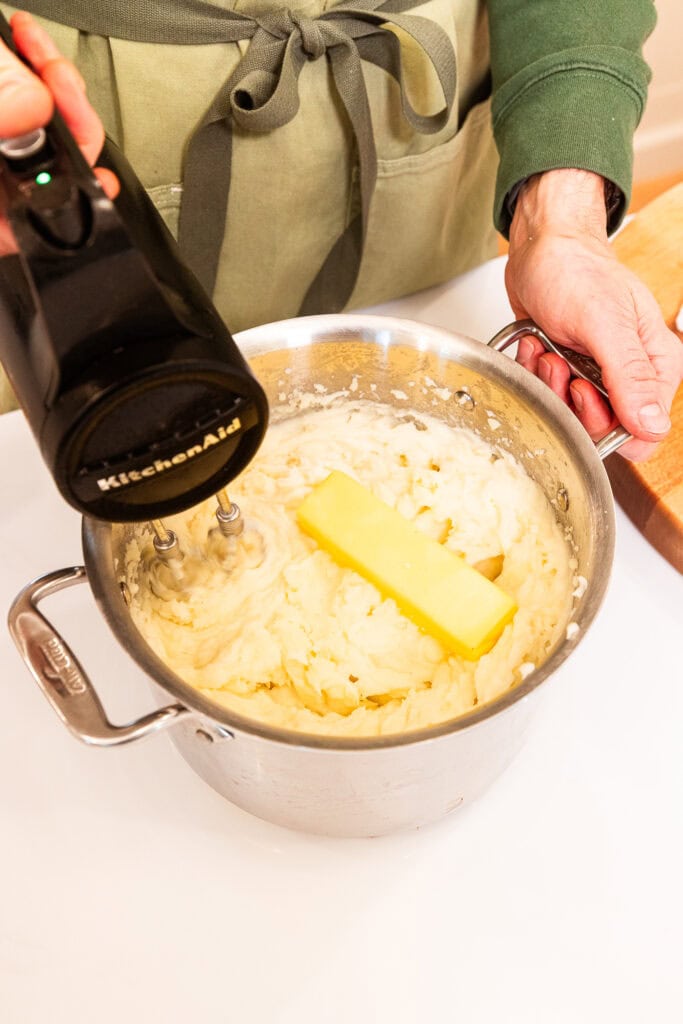 Mixing butter in with mashed potatoes.