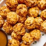 White platter filled with sweet potato puffs with fresh herbs sprinkled on top.