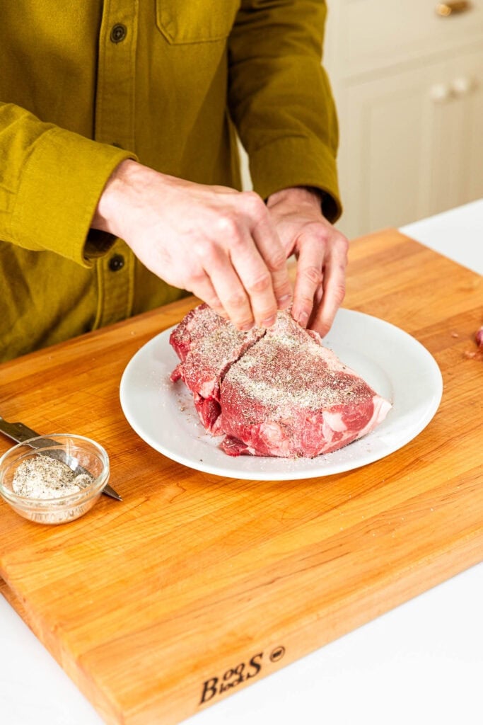 Adding a salt mixture to a cut of pork.
