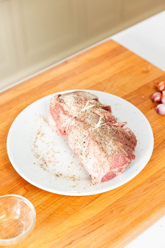 A cut of pork trussed on a plate.